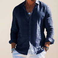 Man wearing the navy Taormina linen shirt open-collared with white trousers