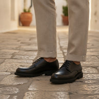 Man wearing the Looksmaxxing Genova elevator derby on a Mediterranean street