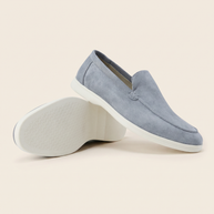 Pair of grey-blue Italian Cut suede loafers, one turned to show the white sole